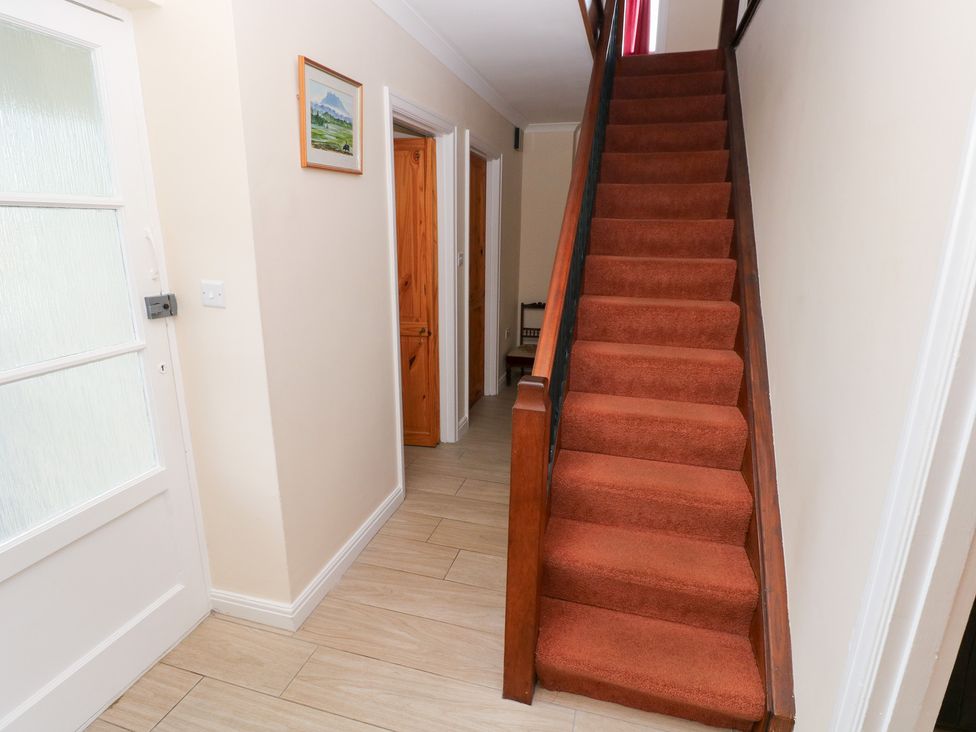 A hallway with a staircase and doors at Cherry Trees in Haverfordwest