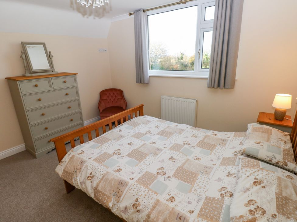 A bedroom with a bed, dresser, and chair at Cherry Trees in Haverfordwest