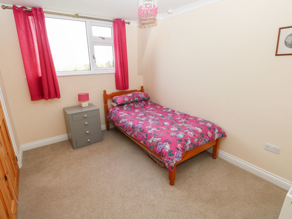 A bedroom with a bed, bedside table, and window at Cherry Trees in Haverfordwest
