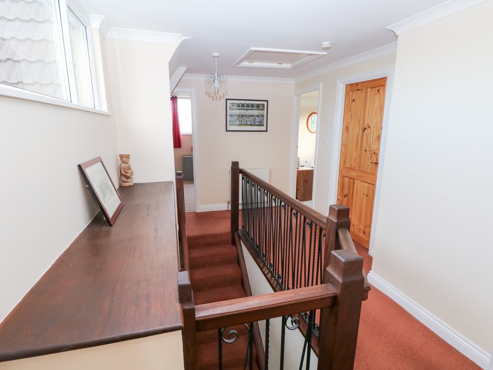A hallway with stairs and a wooden railing at Cherry Trees in Haverfordwest