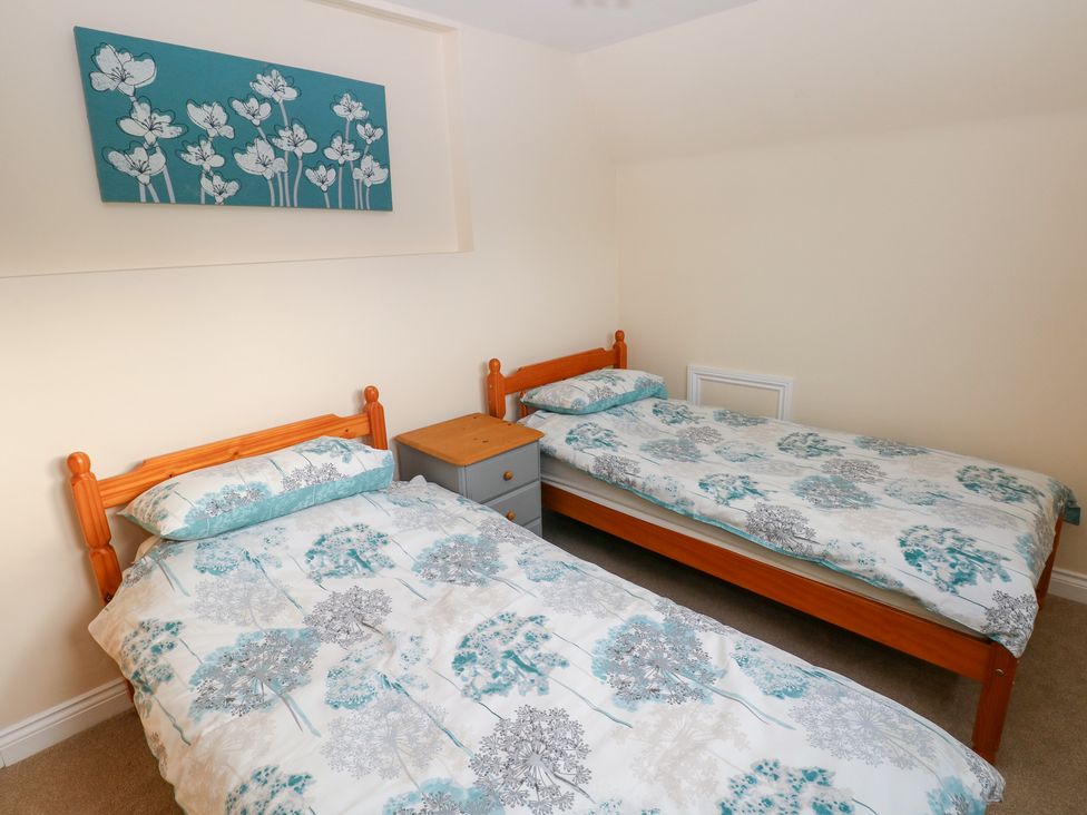 A bedroom with two beds and a nightstand at Cherry Trees in Haverfordwest
