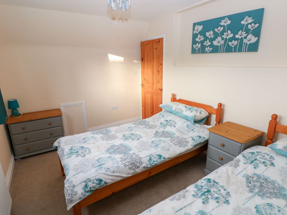 A bedroom with two beds and a bedside table at Cherry Trees in Haverfordwest
