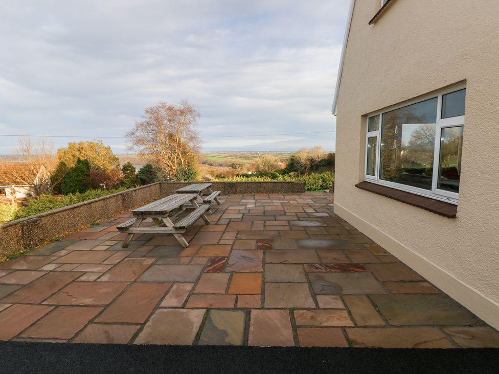 An outdoor area with a table and benches at Cherry Trees, Haverfordwest