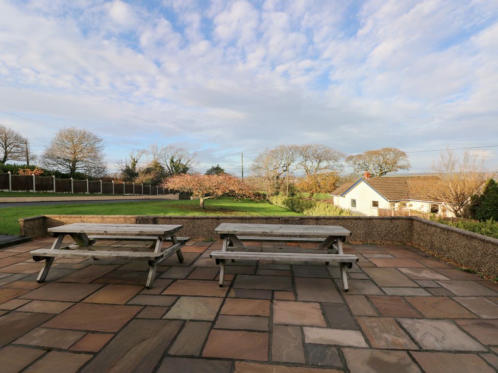 A patio with tables and grass area at Cherry Trees in Haverfordwest