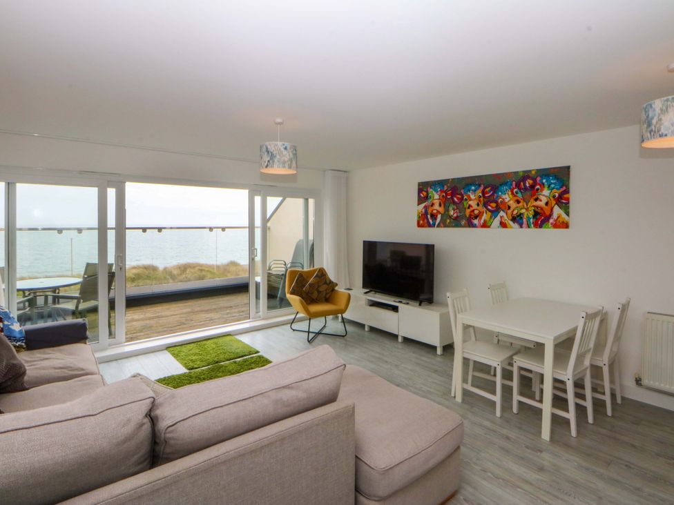 A living room with a sofa and dining area at Welymora in Pwllheli