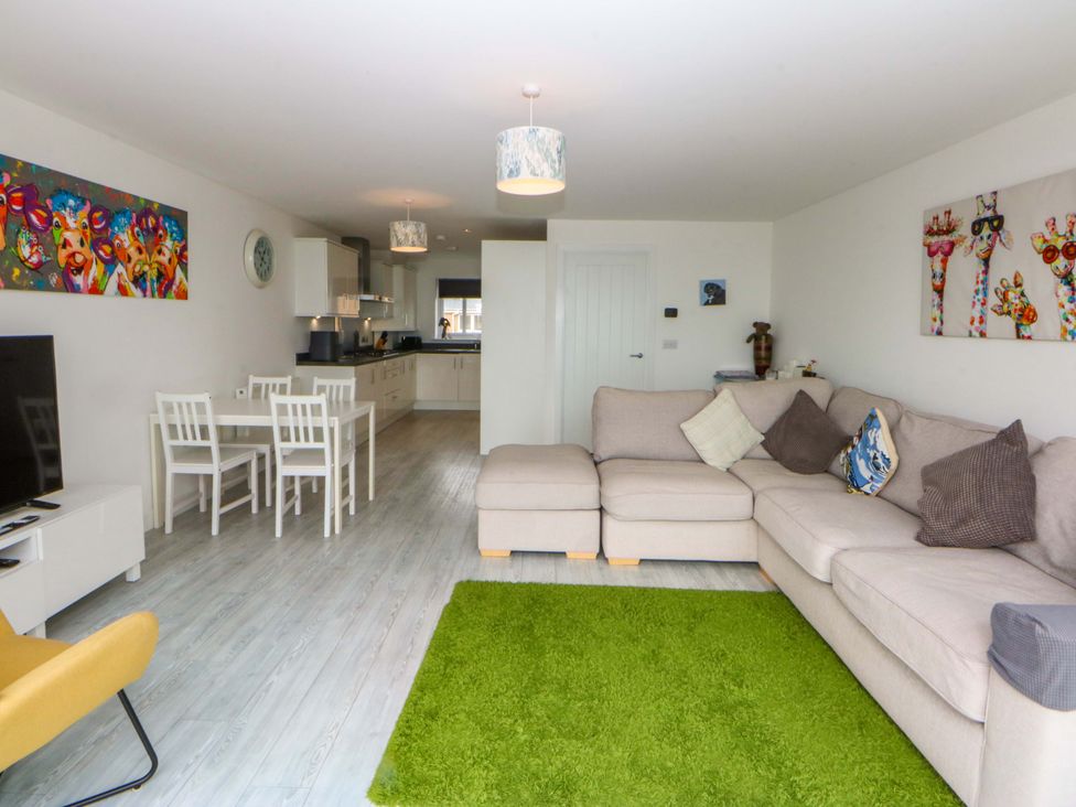 A living room with a sofa and dining area at Welymora Pwllheli