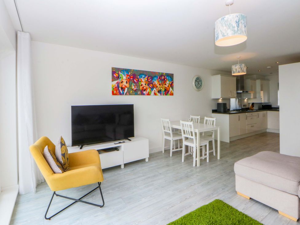 A living room with a television and dining set at Welymora Pwllheli