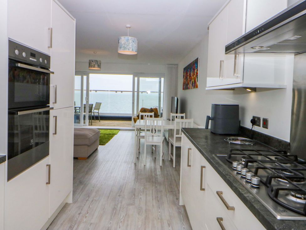 A kitchen with appliances and dining area at Welymora Pwllheli