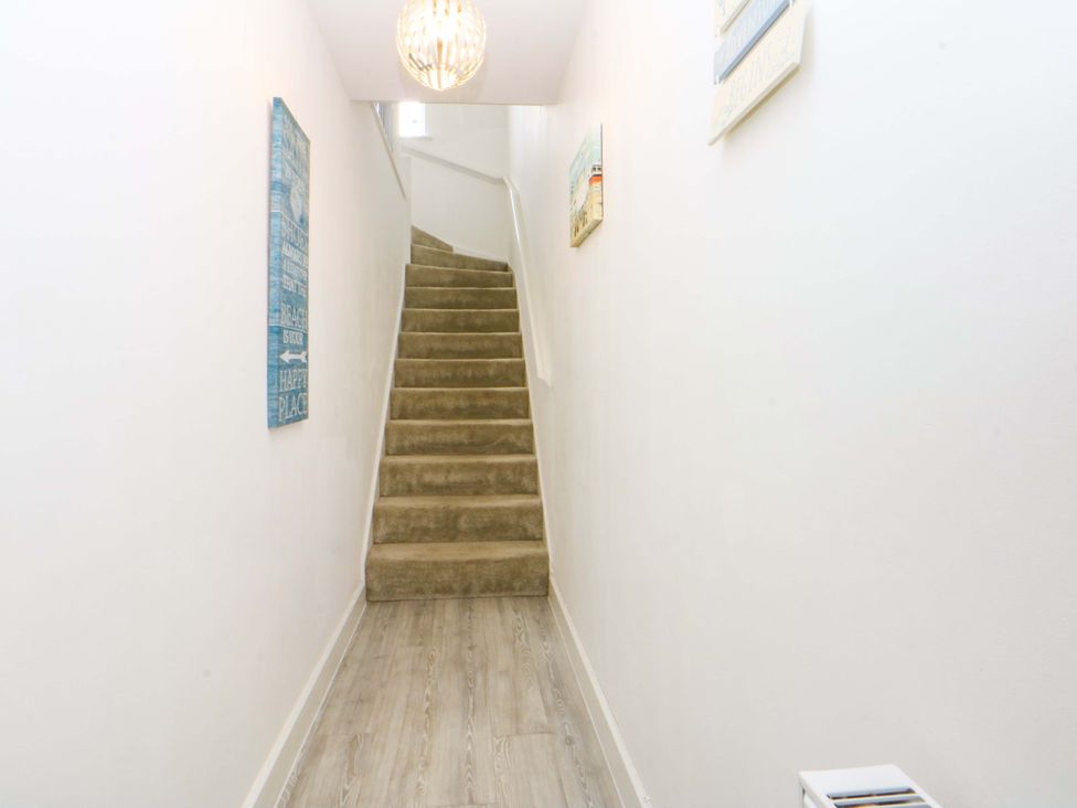 A hallway with a staircase and decorative art at Welymora in Pwllheli