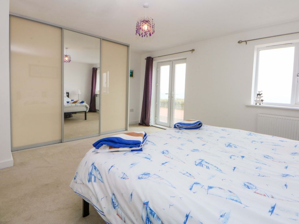A bedroom featuring a bed with bedding and mirrored wardrobe at Welymora in Pwllheli