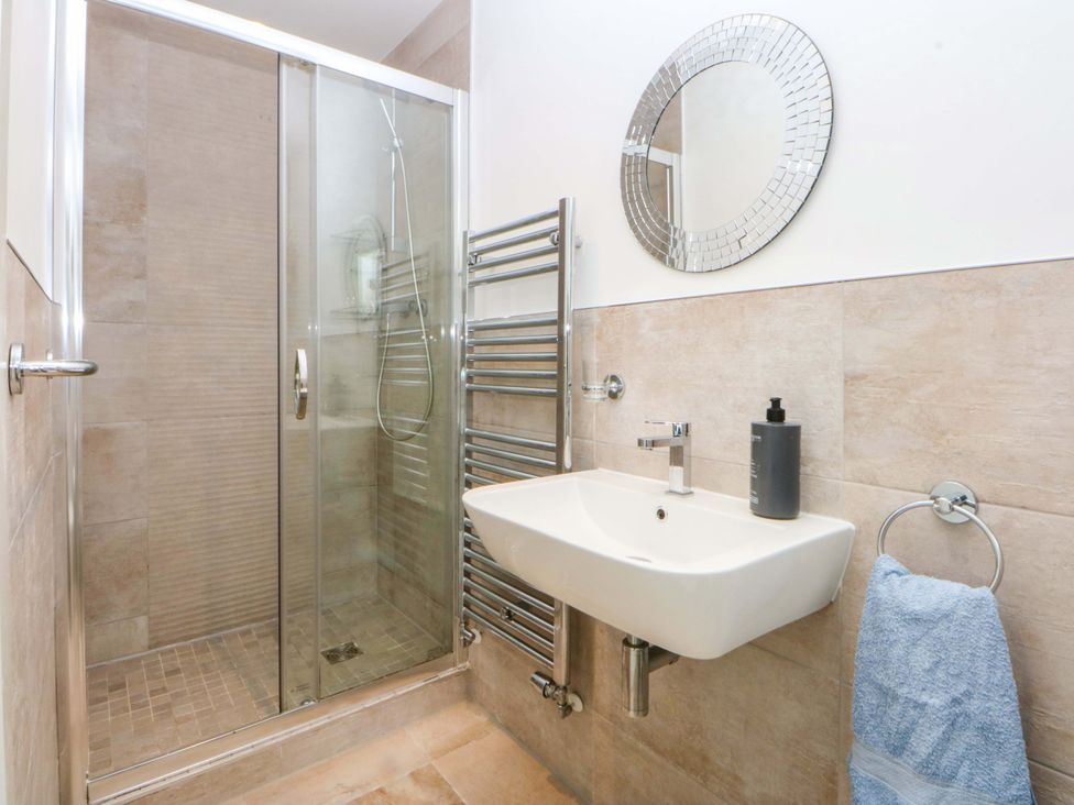 A bathroom with a shower, sink, mirror and towel rack at Welymora Pwllheli