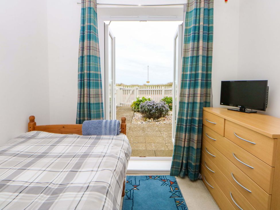 A bedroom with a bed and television at Welymora in Pwllheli