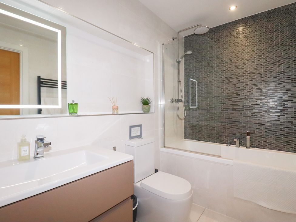 A bathroom with a mirror, sink, toilet, and shower at Seaspell Beach House in Constantine Bay