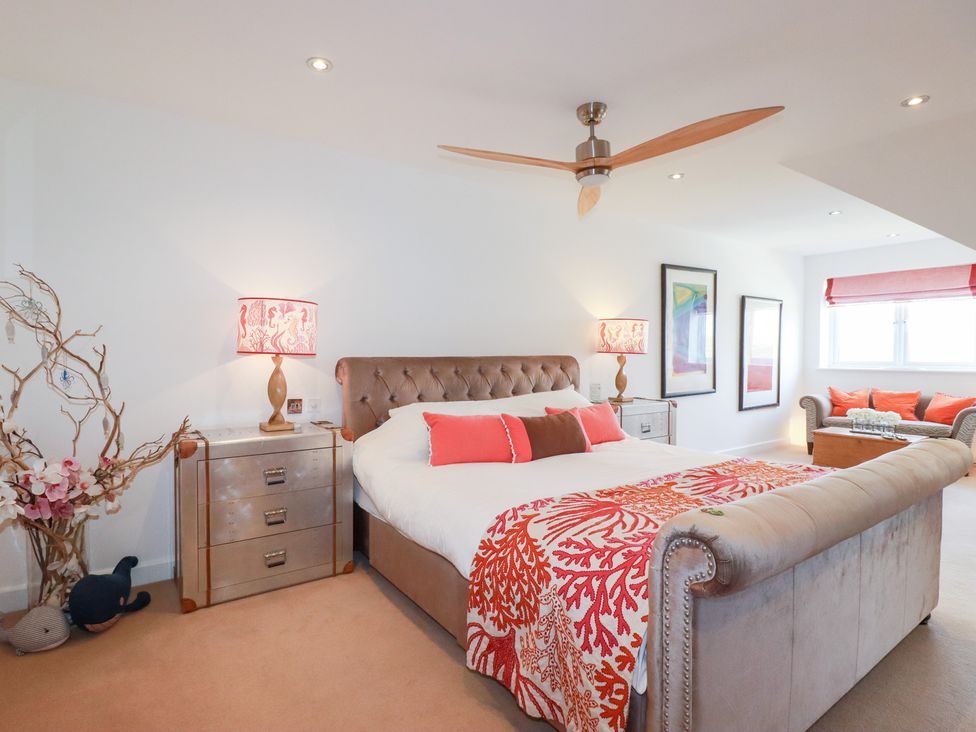 A bedroom with a bed and sofa at Seaspell Beach House in Constantine Bay