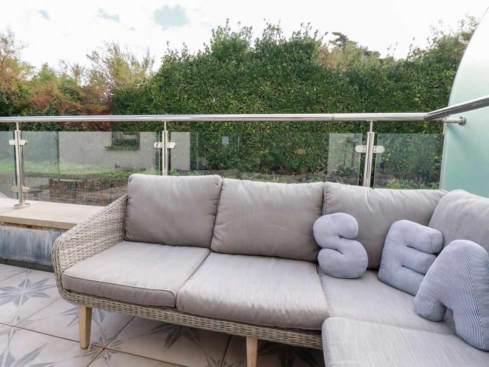 An outdoor seating area with a couch and pillows at Seaspell Beach House, Constantine Bay