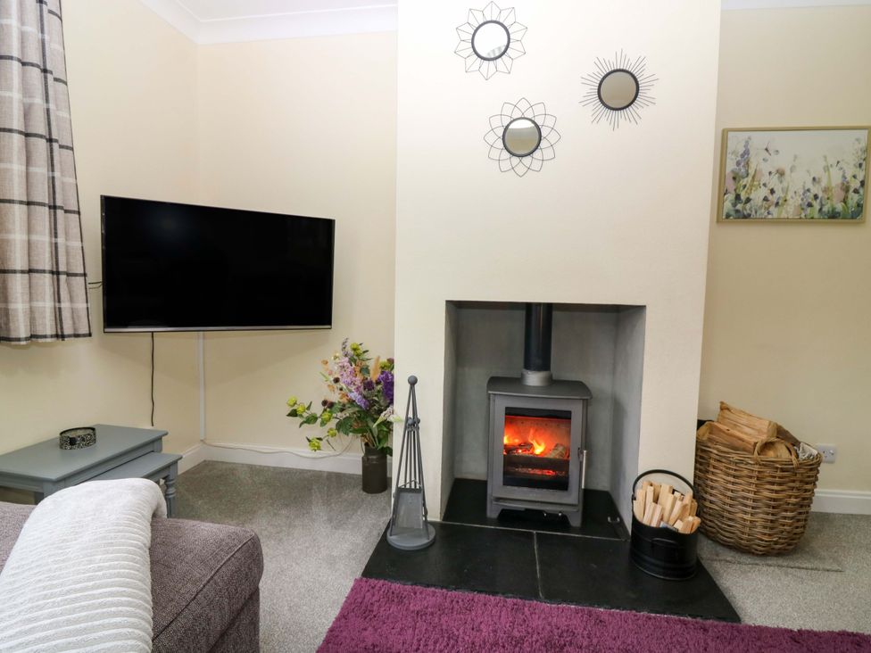 A living room with a fireplace and television at Falla Farmhouse in Jedburgh