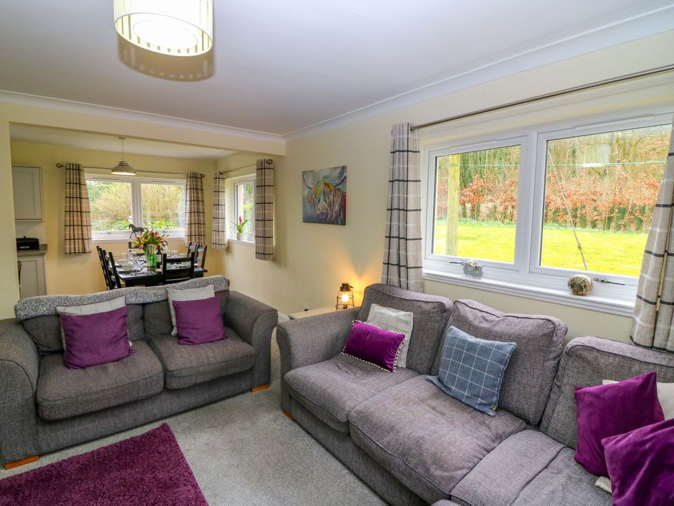 A living room with a sofa and dining area at Falla Farmhouse in Jedburgh