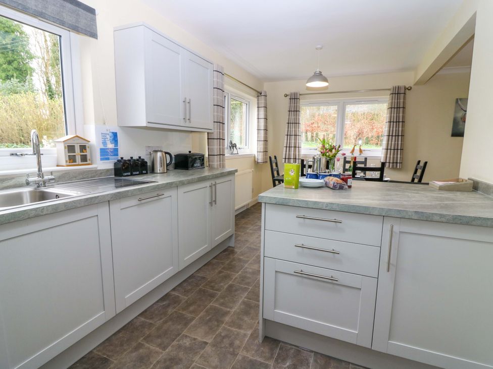 A kitchen with cabinets and a dining table at Falla Farmhouse in Jedburgh