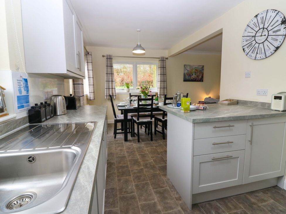 A kitchen with a sink, cabinets, and dining area at Falla Farmhouse in Jedburgh