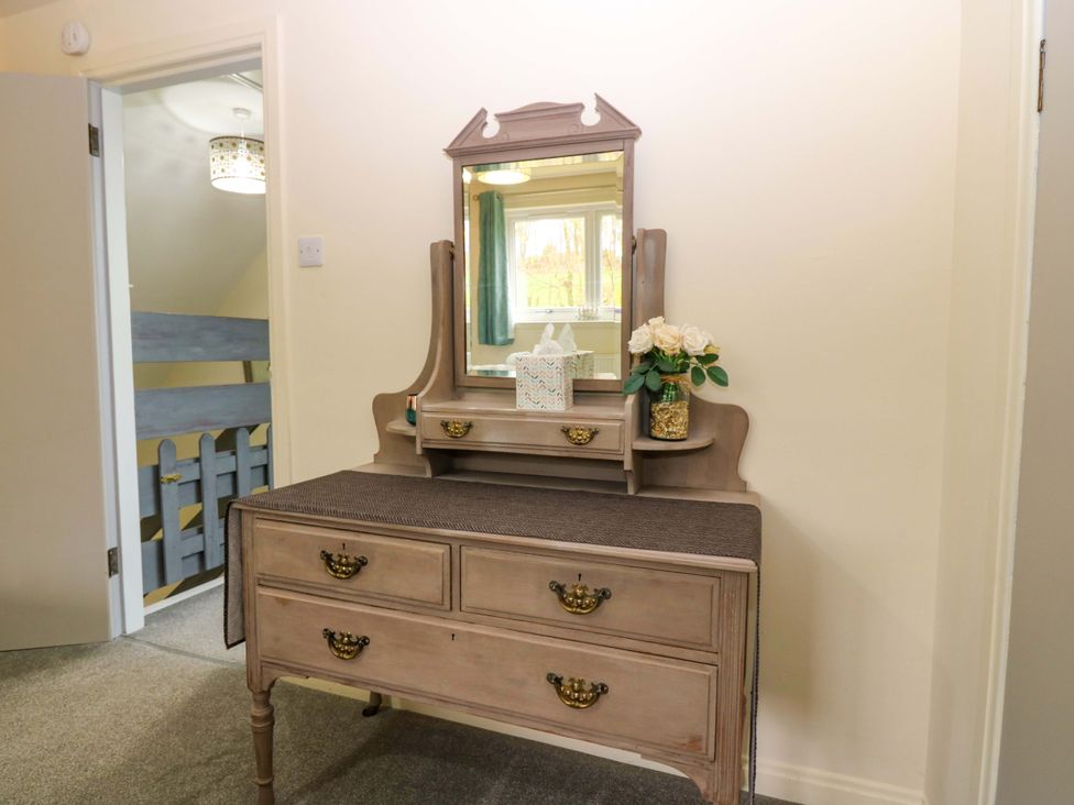 A dressing table with a mirror and flowers at Falla Farmhouse in Jedburgh