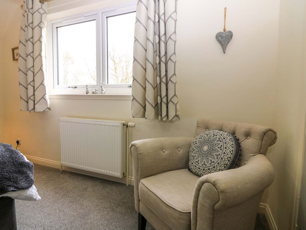 A chair with a cushion near a window at Falla Farmhouse in Jedburgh