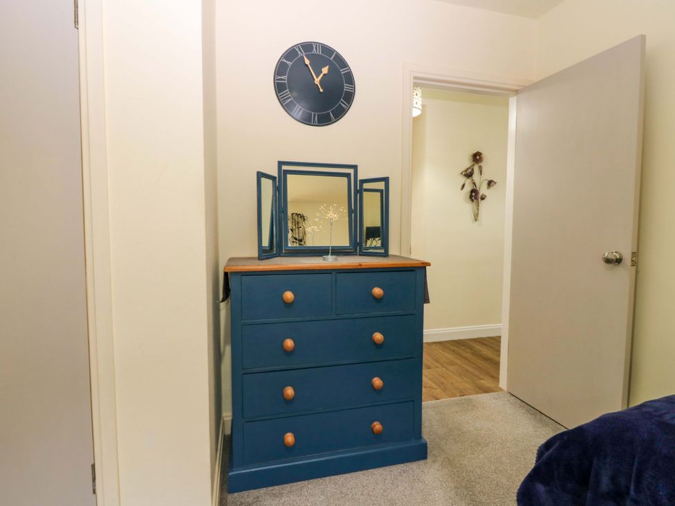A dresser with a clock and mirror in a bedroom at Falla Farmhouse Jedburgh