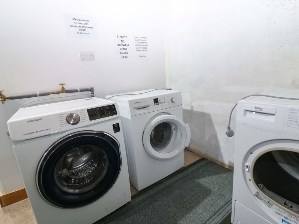 A laundry room with washing machines and a tumble dryer at Falla Farmhouse in Jedburgh