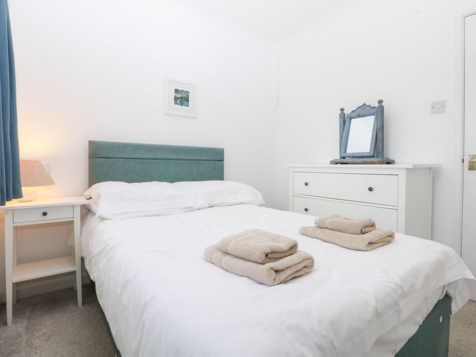 A bedroom with a bed and towels on the bed at Eryl in Nefyn