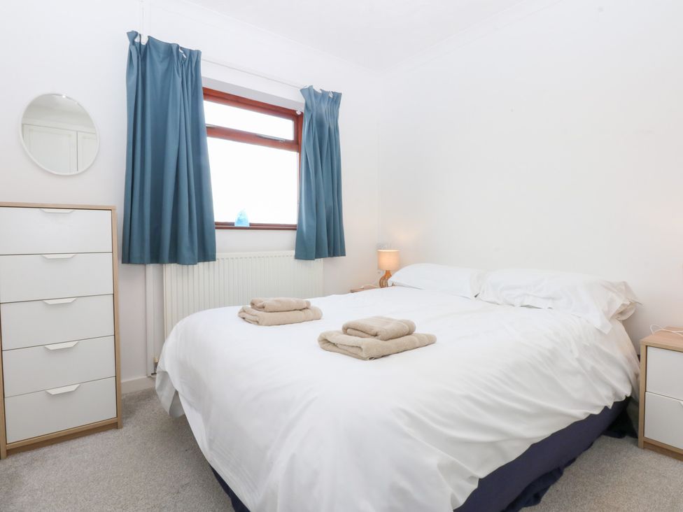 A bedroom with a bed and a dresser at Eryl in Nefyn