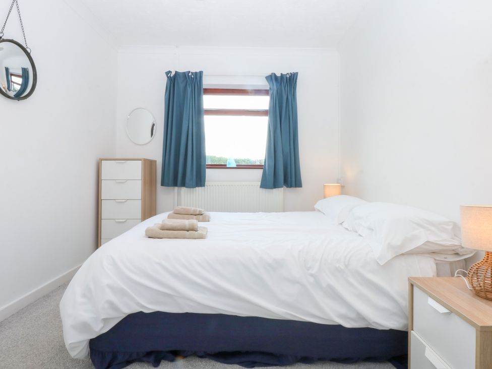 A bedroom with a bed and dresser at Eryl in Nefyn