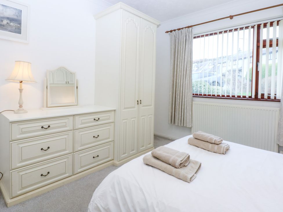 A bedroom with a lamp and dresser at Eryl in Nefyn