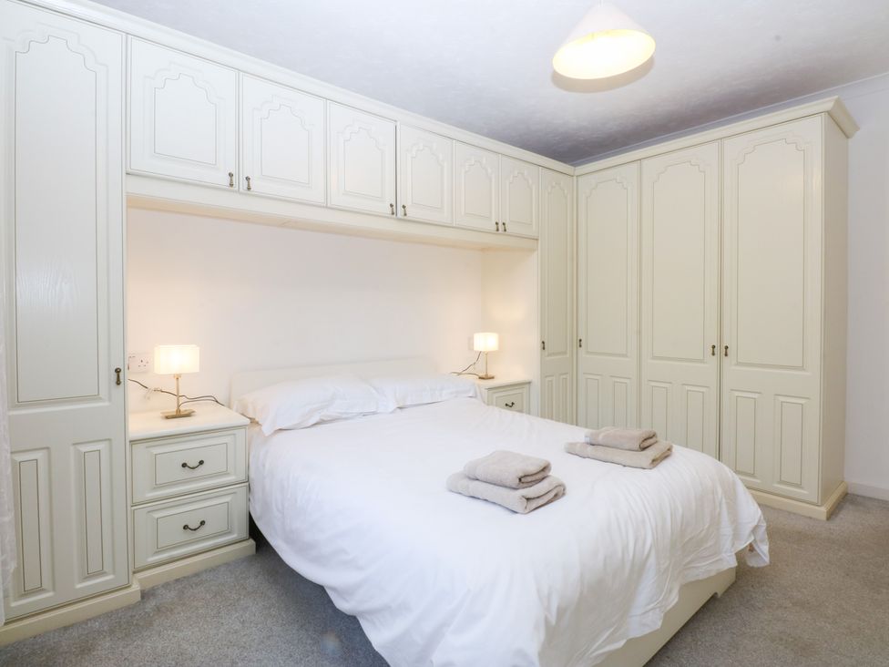 A bedroom with a bed and wardrobe at Eryl in Nefyn