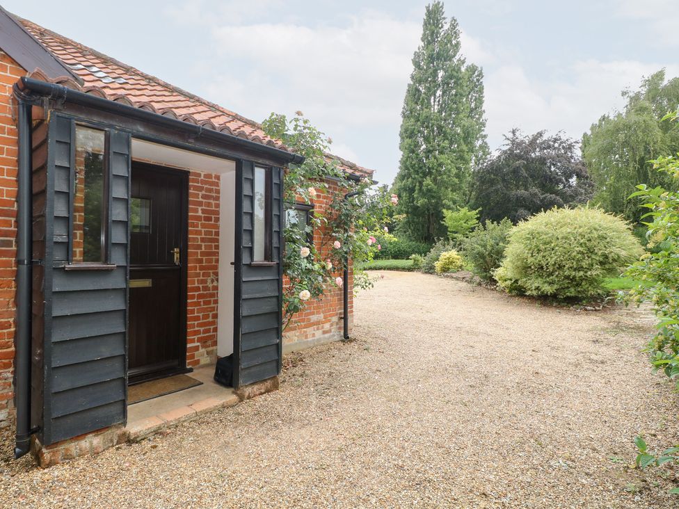 An entrance with a gravel path and a rose bush at Lowbrook Cottage Dickleburgh near Diss