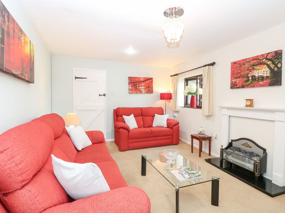 A living room with a sofa, coffee table, and fireplace at Lowbrook Cottage in Dickleburgh near Diss