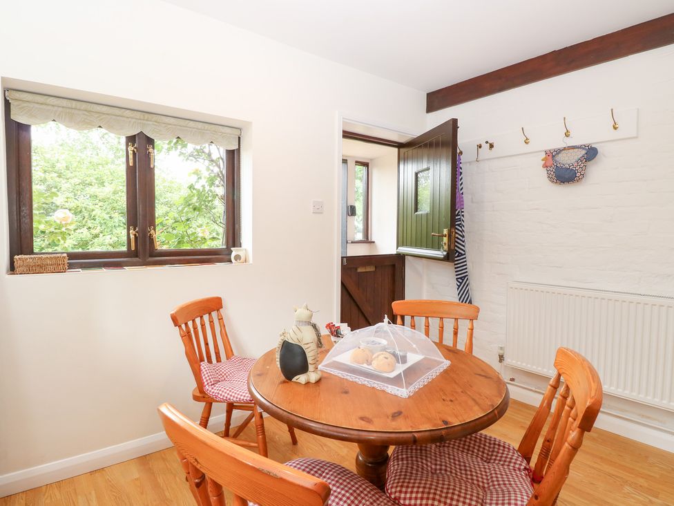 A dining room with a round table and wooden chairs at Lowbrook Cottage in Dickleburgh near Diss