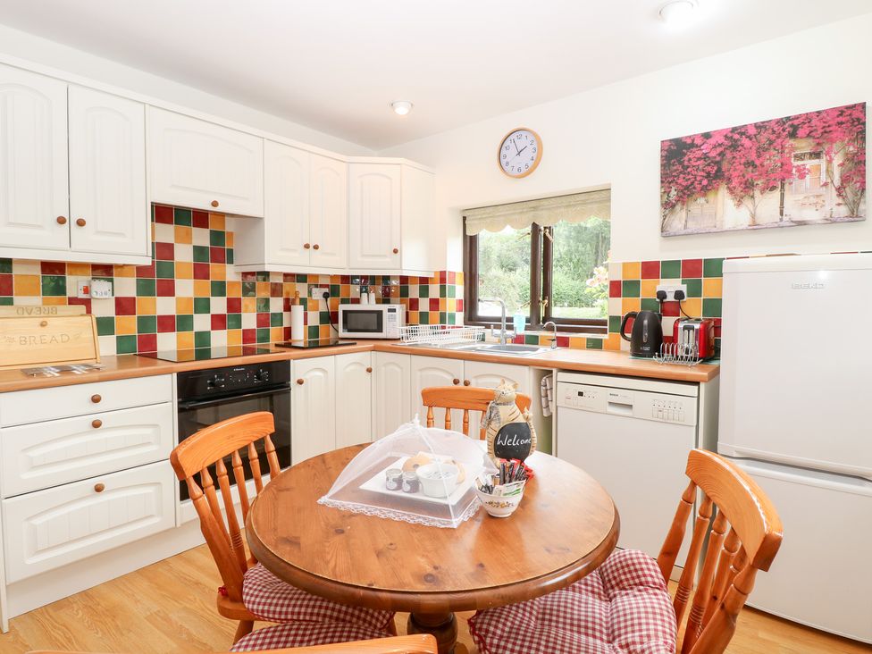 A kitchen with cabinets, appliances, and a round table at Lowbrook Cottage in Dickleburgh near Diss