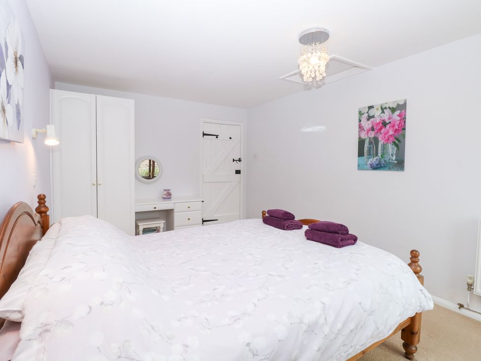 A bedroom with a bed and a cabinet at Lowbrook Cottage in Dickleburgh near Diss