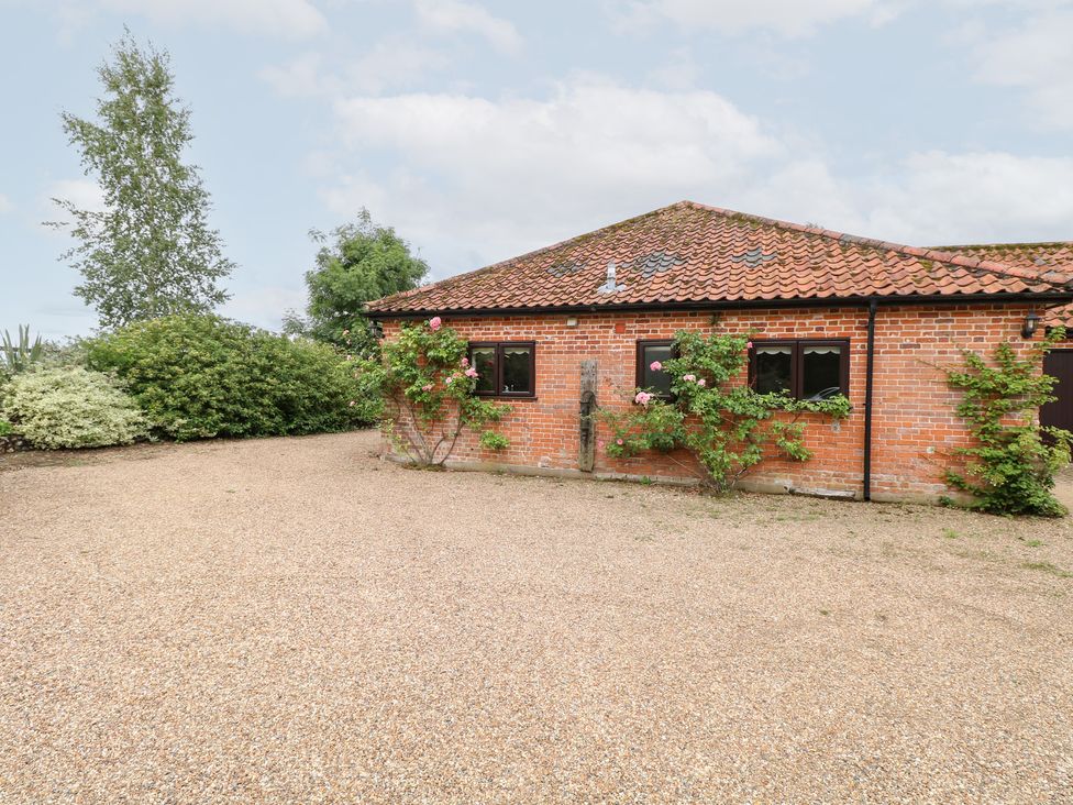 A brick building with windows and a gravel driveway at Lowbrook Cottage Dickleburgh near Diss