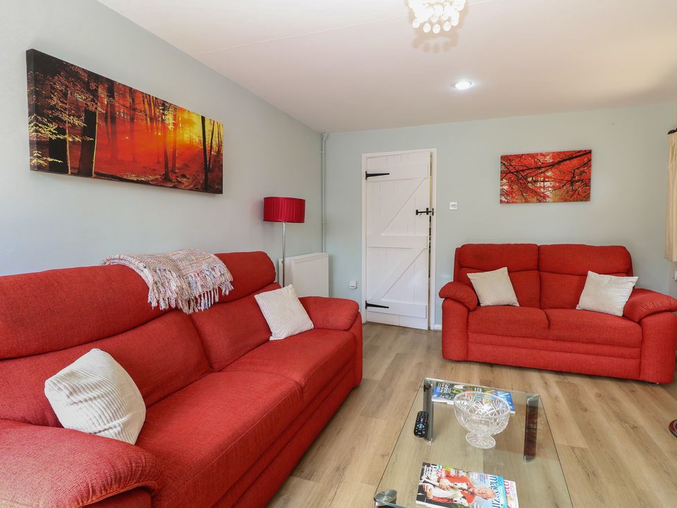 A living room with red sofas and a coffee table at Lowbrook Cottage in Dickleburgh near Diss