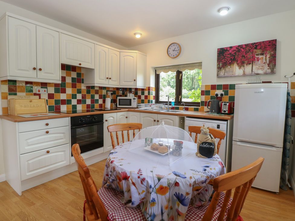 A kitchen with cabinets and a table with chairs at Lowbrook Cottage Dickleburgh near Diss