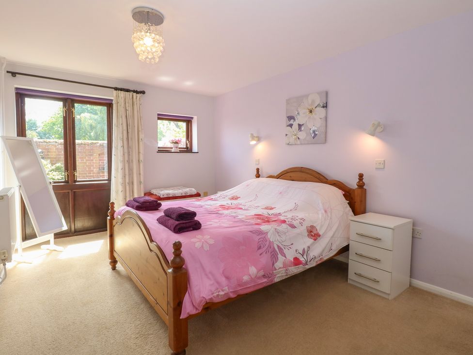 A bedroom with a bed and windows at Lowbrook Cottage in Dickleburgh near Diss