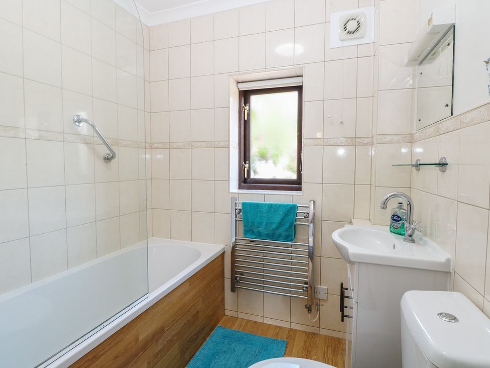 A bathroom with a bath, toilet, sink and towel rail at Lowbrook Cottage in Dickleburgh near Diss