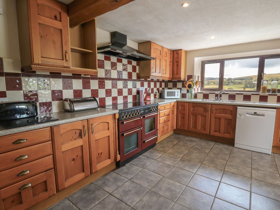 A kitchen with wooden cabinets and appliances at Glanyrafon in St Harmon