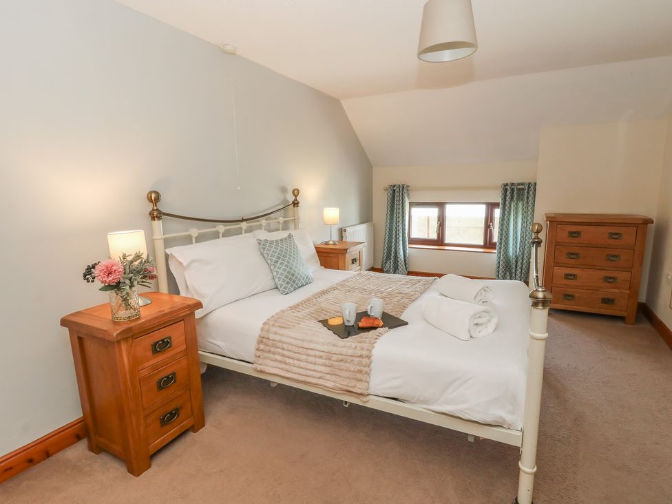 A bedroom with a bed and nightstands at Glanyrafon in St Harmon