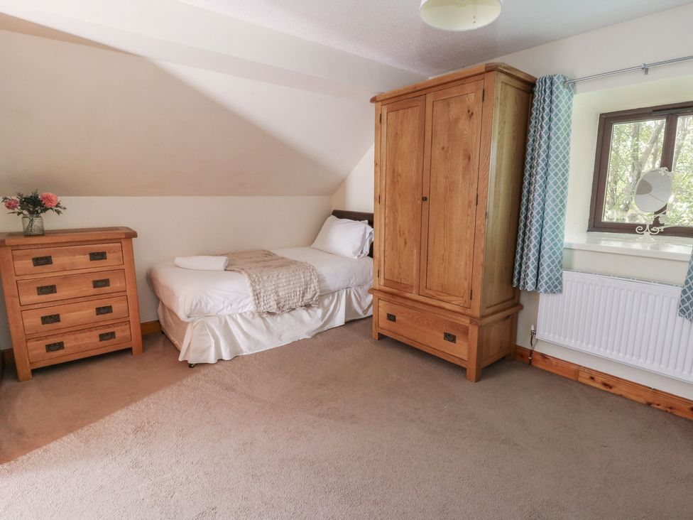 A bedroom with a bed and dresser at Glanyrafon in St Harmon