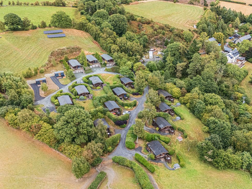 An aerial view of cabins surrounded by trees and fields at Glanyrafon Bungalow in St Harmon