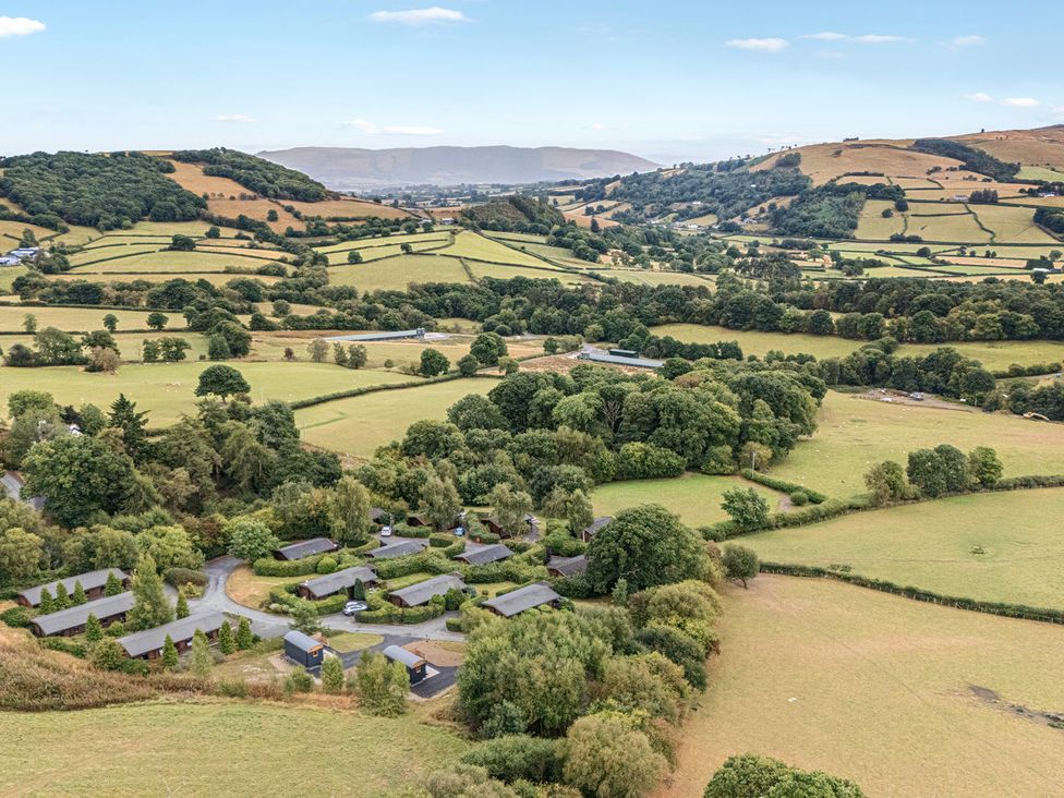 An aerial view of fields and cabins at Glanyrafon Bungalow in St Harmon