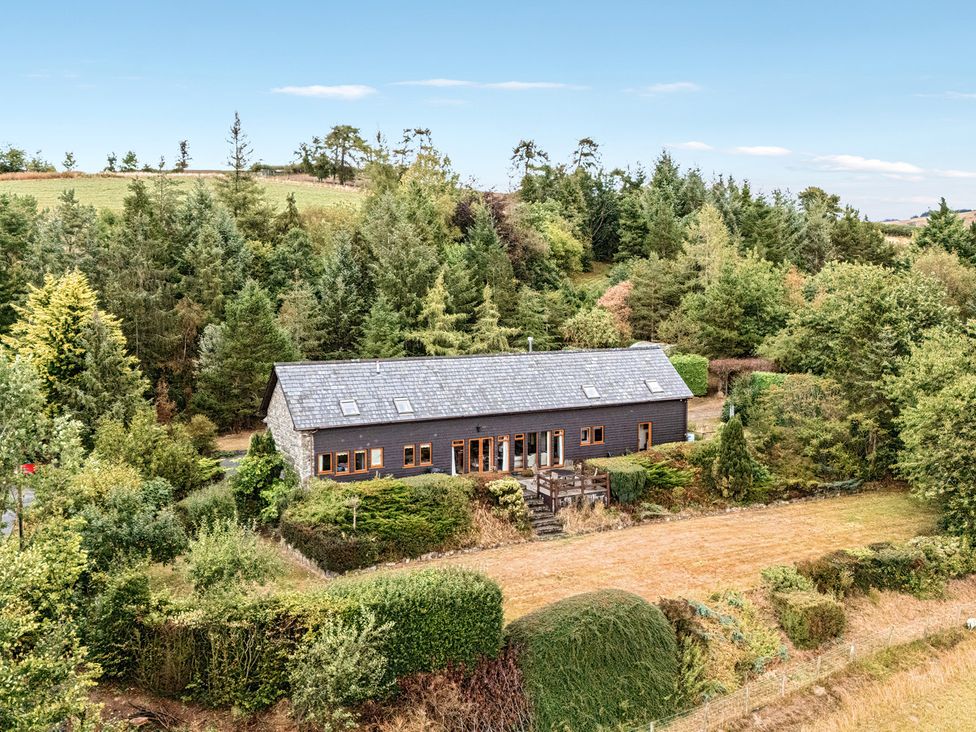 A house surrounded by trees and garden at Glanyrafon Bungalow in St Harmon