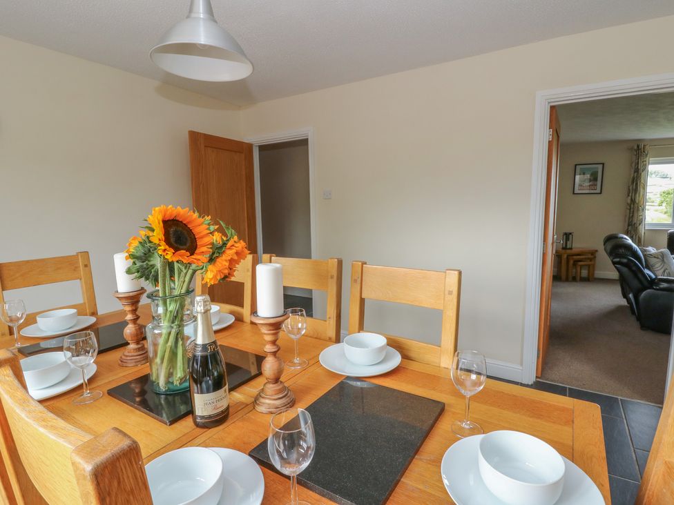 A dining room with a table set for a meal at Glanyrafon Bungalow St Harmon