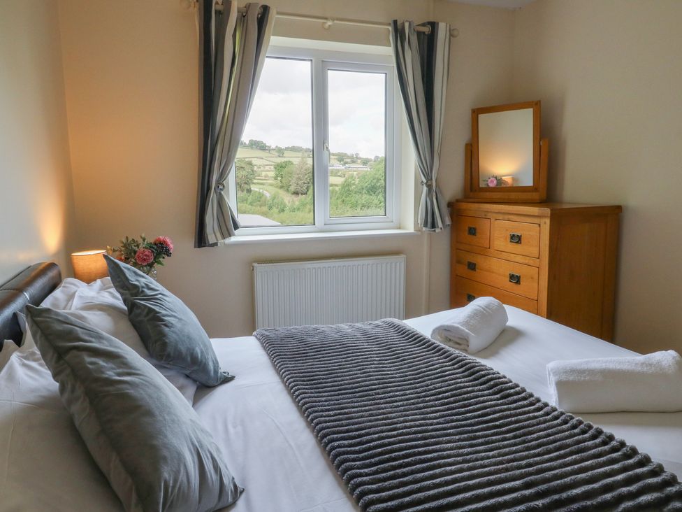 A bedroom with a bed and window view at Glanyrafon Bungalow, St Harmon